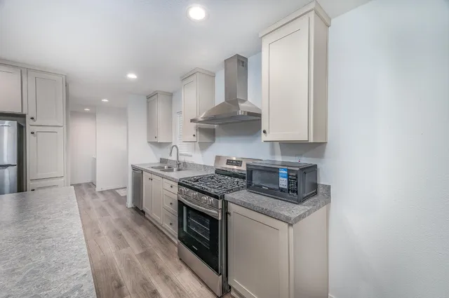 a kitchen with stainless steel appliances granite countertop a stove a sink and a refrigerator