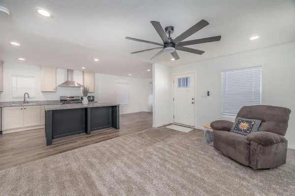 a living room with stainless steel appliances kitchen island granite countertop a couch and cabinets