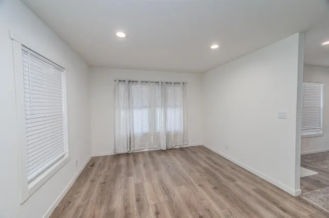 an empty room with wooden floor and windows