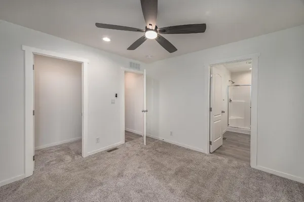 an empty room with closet and a ceiling fan