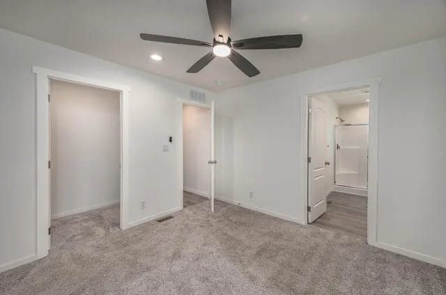 an empty room with closet and a ceiling fan