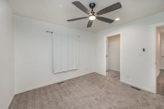 an empty room with a ceiling fan and a fan