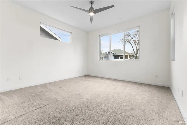 an empty room with windows and fan