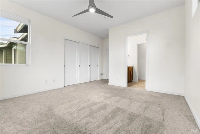 an empty room with chandelier fan and windows