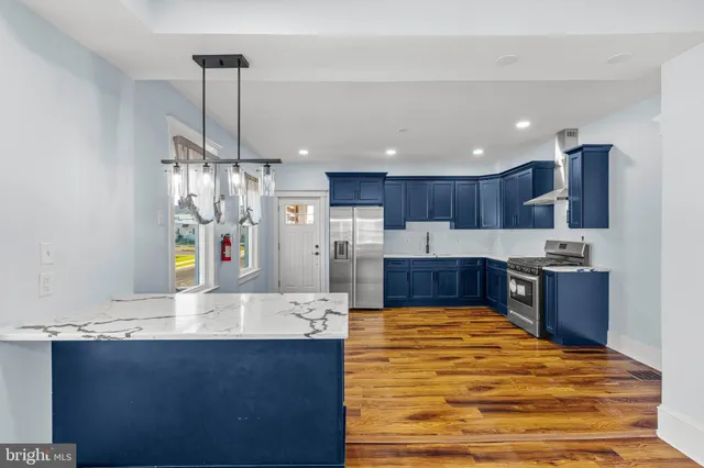 a large kitchen with stainless steel appliances a large counter top a stove and a refrigerator