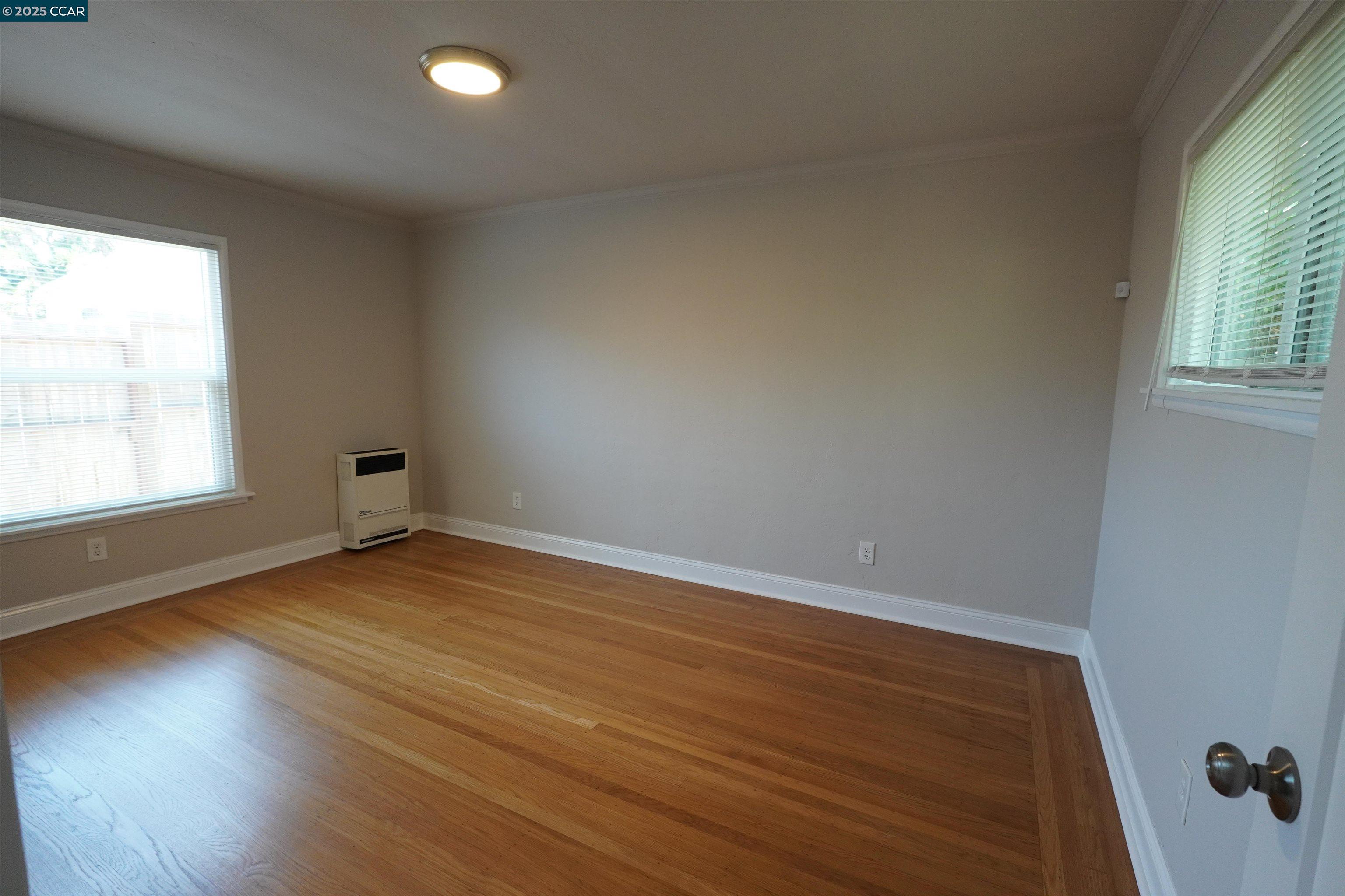 2645 Maxwell Avenue Oakland, CA 94619 - Photo 14 of 19 an empty room with wooden floor and windows