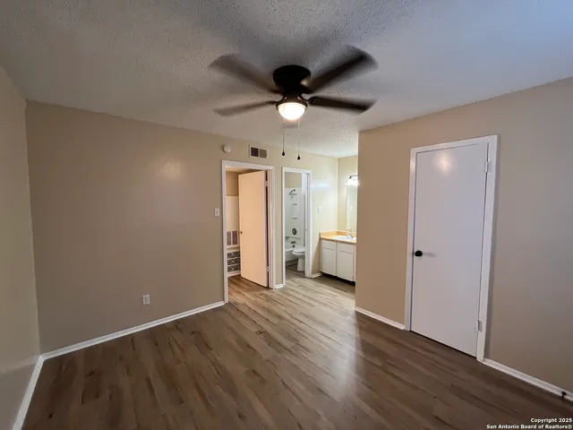 an empty room with wooden floor and a ceiling fan