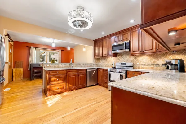 a kitchen with stainless steel appliances granite countertop a sink a stove and a wooden cabinets