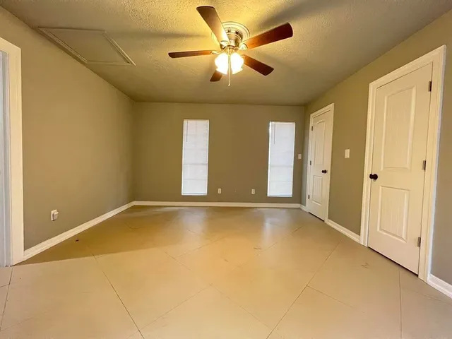 a view of an empty room with window and a ceiling fan