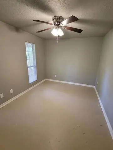 an empty room with windows and fan