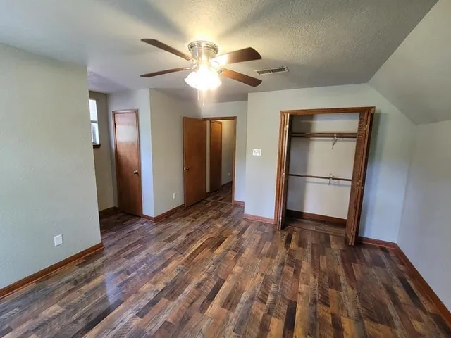 an empty room with wooden floor and a ceiling fan