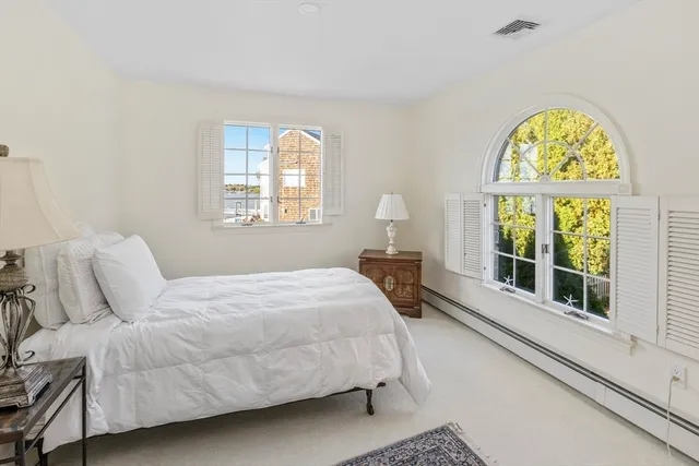a spacious bedroom with a bed a dresser and a large mirror