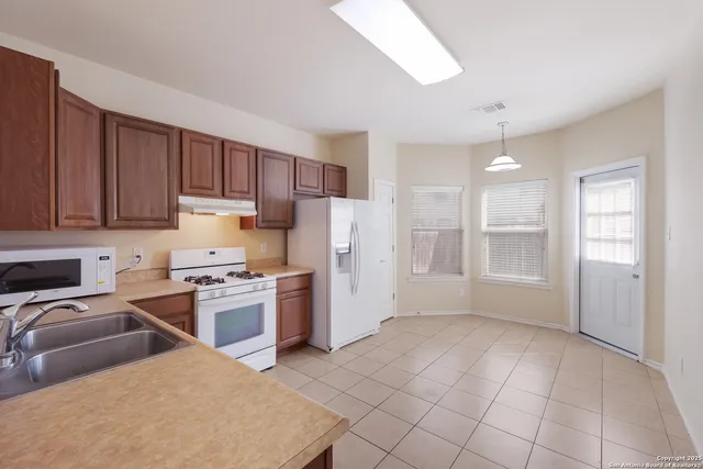 a kitchen with stainless steel appliances granite countertop a refrigerator stove top oven and sink