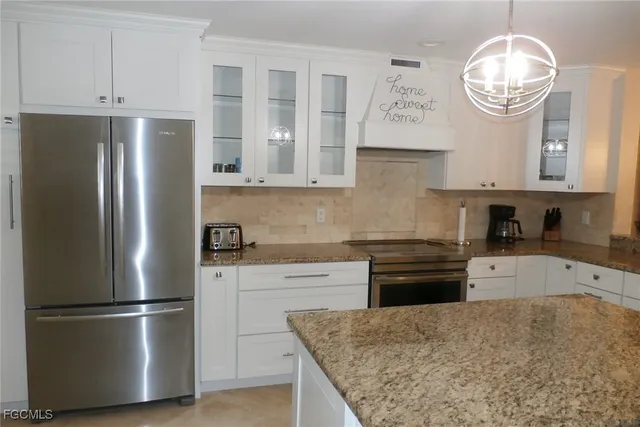 a kitchen with stainless steel appliances granite countertop a refrigerator a stove and a sink