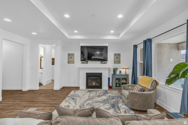 2454 West Jackson Street Mapleton, UT 84664 - Photo 11 of 63 Living room featuring wood finished floors, recessed lighting, a glass covered fireplace, and a tray ceiling