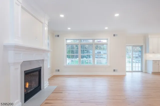 a view of an empty room with wooden floor and a fireplace