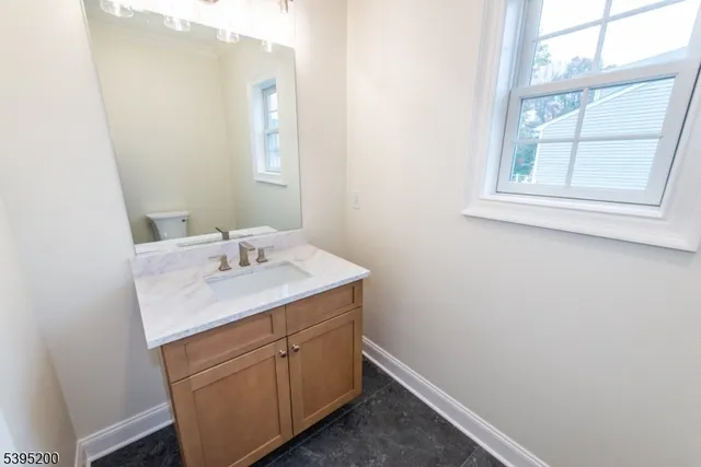 a bathroom with a granite countertop sink and a window
