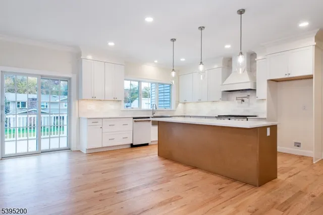 a large kitchen with stainless steel appliances sink a large window and wooden floor