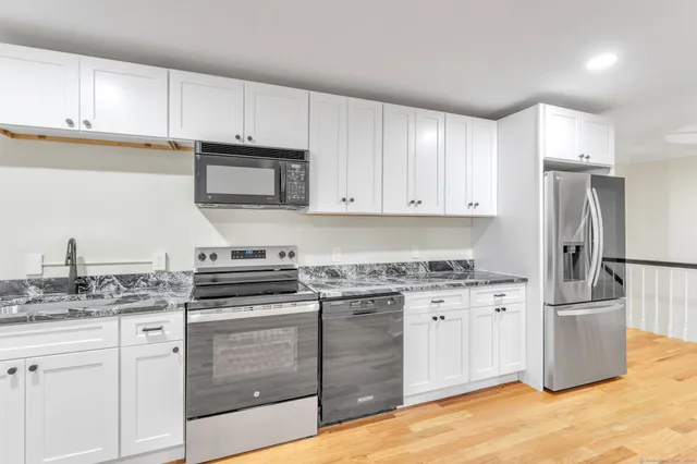 a kitchen with stainless steel appliances granite countertop a stove a refrigerator and a white cabinets