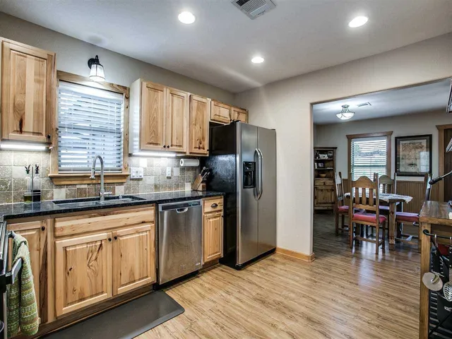 a kitchen with stainless steel appliances granite countertop a refrigerator and wooden cabinets