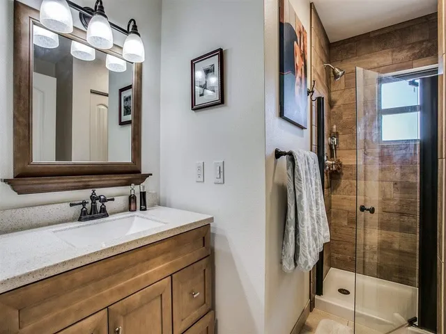 a bathroom with a sink a mirror a vanity and shower