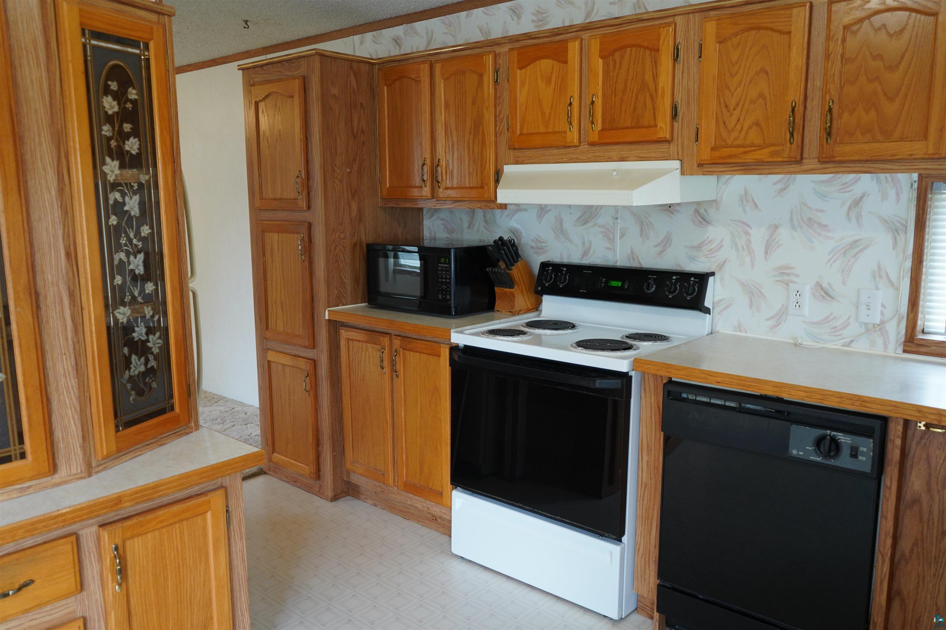 47 Coban Drive Duluth, MN 55808 - Photo 12 of 23 Kitchen with black appliances, light countertops, brown cabinetry, premium range hood, and crown molding