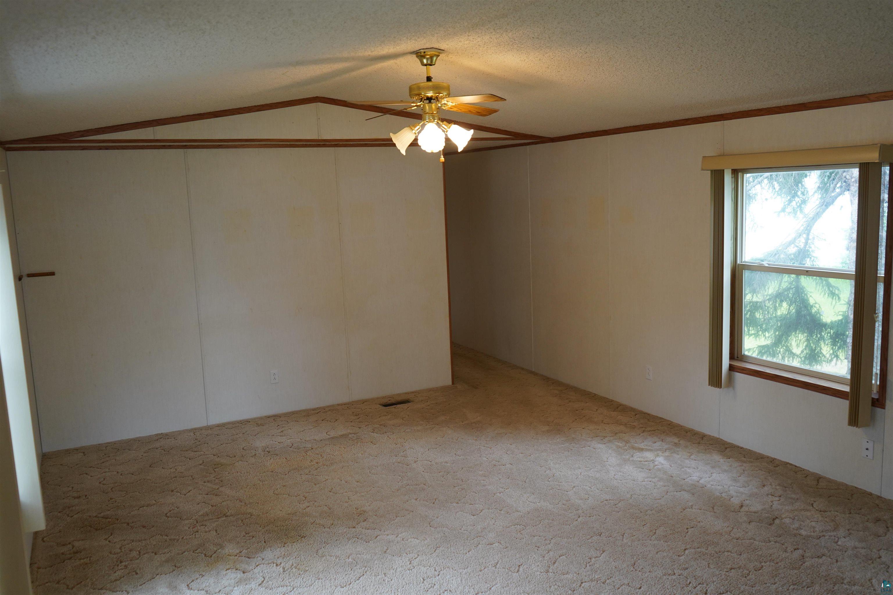 47 Coban Drive Duluth, MN 55808 - Photo 14 of 23 Carpeted spare room with ceiling fan, vaulted ceiling, and a textured ceiling