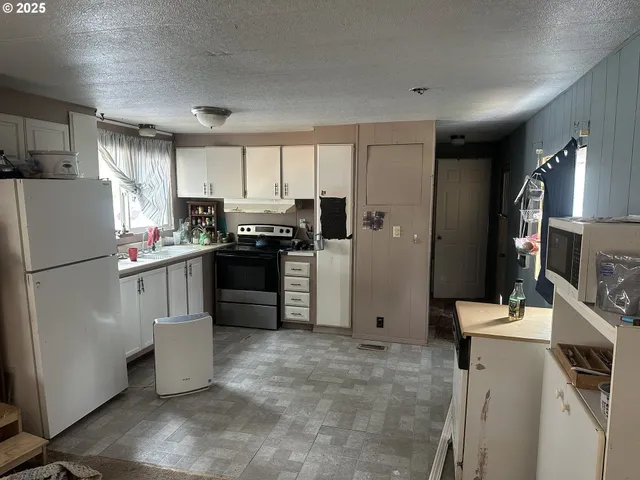 a kitchen with refrigerator a microwave a stove and white cabinets