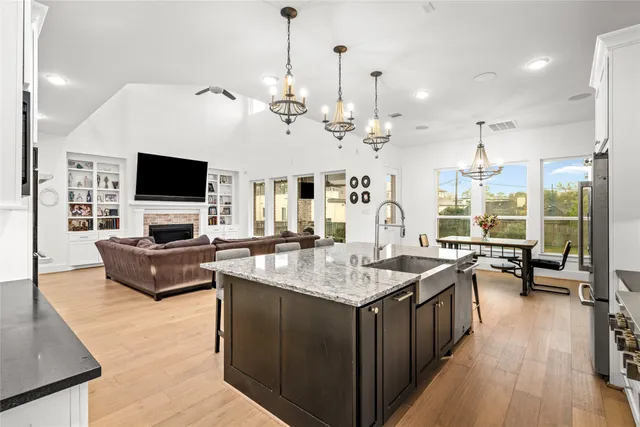 a living room with stainless steel appliances granite countertop furniture a fireplace and a flat screen tv