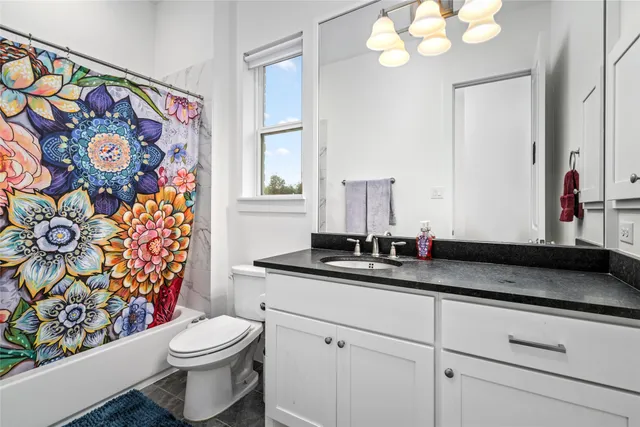 a bathroom with a granite countertop sink mirror vanity and toilet