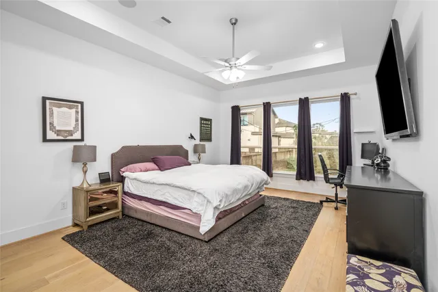 a spacious bedroom with a bed flat screen tv and a large window