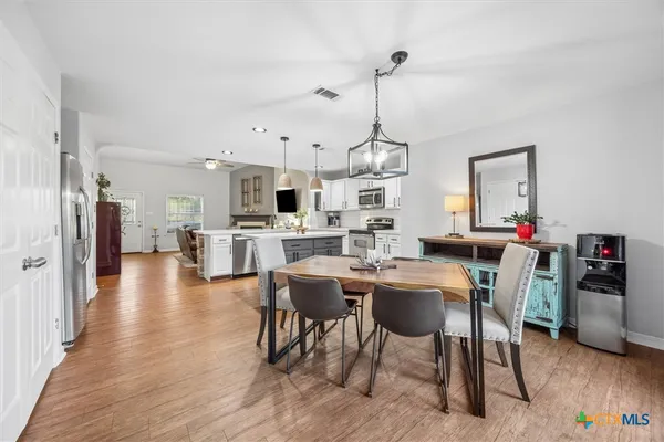 a view of a dining room and livingroom with furniture wooden floor a rug a chandelier