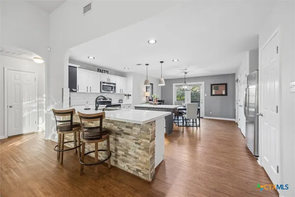 a kitchen with stainless steel appliances granite countertop dining table chairs and a refrigerator