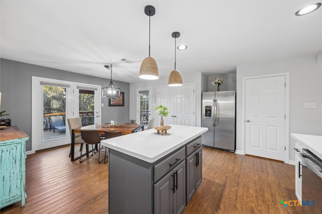 1328 Cottonwood Road Fischer, TX 78623 - Photo 16 of 35 a kitchen with stainless steel appliances granite countertop a refrigerator a sink dishwasher a dining table and chairs with wooden floor