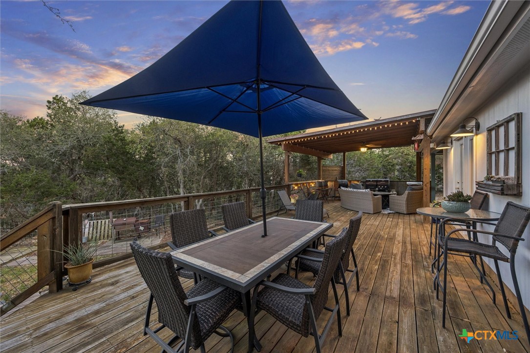 1328 Cottonwood Road Fischer, TX 78623 - Photo 28 of 35 a view of deck with table and chairs under an umbrella with wooden floor