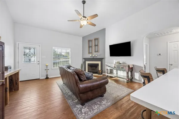 a living room with furniture a fireplace a flat screen tv and wooden floor