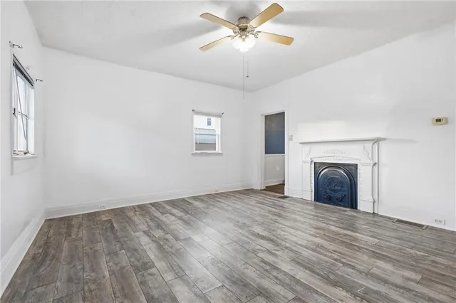 a view of a livingroom with a fireplace ceiling fan and windows
