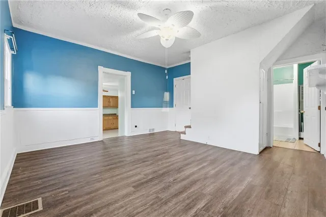 a view of empty room with wooden floor and ceiling fan