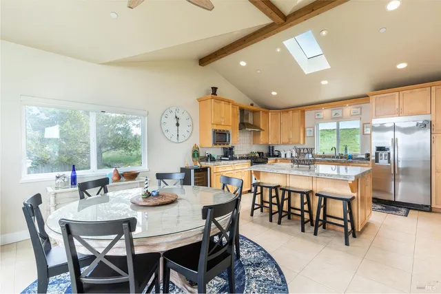 a dining room with stainless steel appliances granite countertop a table and chairs