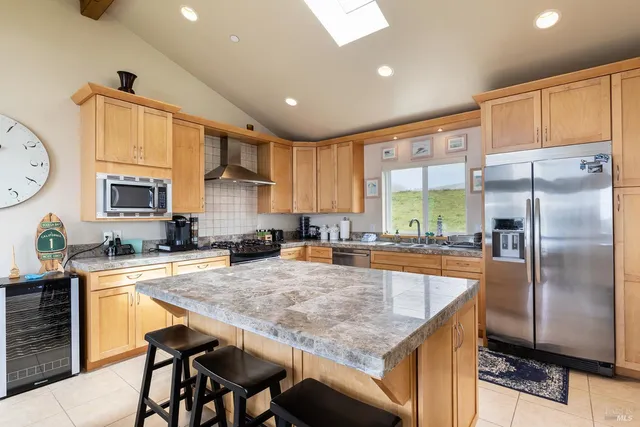 a kitchen with granite countertop a table chairs microwave and refrigerator