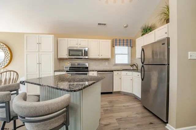 a kitchen with a refrigerator a stove a sink and dishwasher with wooden floor