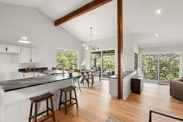 a dining hall with stainless steel appliances granite countertop wooden floor a stove a sink a dining table and chairs with wooden floor