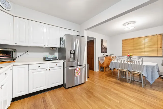 a kitchen with stainless steel appliances granite countertop a refrigerator a stove a sink and white cabinets with wooden floor