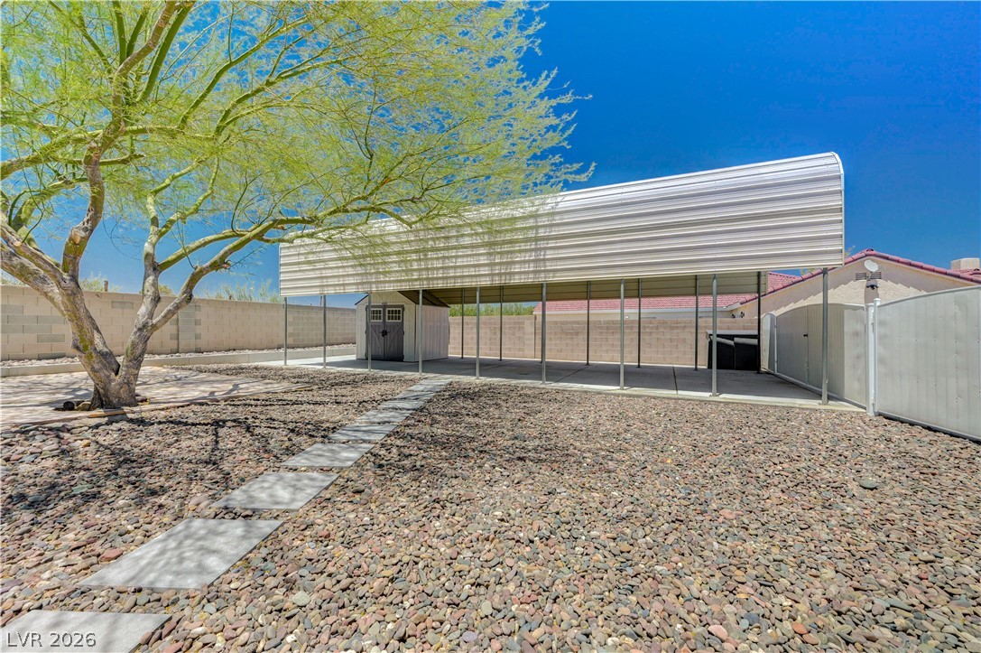 7631 Bermuda Road Las Vegas, NV 89123 - Photo 35 of 64 A spacious backyard with mature trees, a detached shed, and a covered parking area for versatile outdoor living.