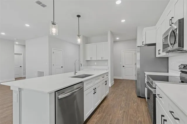 a kitchen with kitchen island a sink stainless steel appliances and cabinets