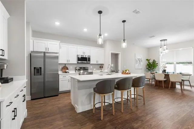 a large kitchen with kitchen island a white counter space a sink stainless steel appliances and cabinets