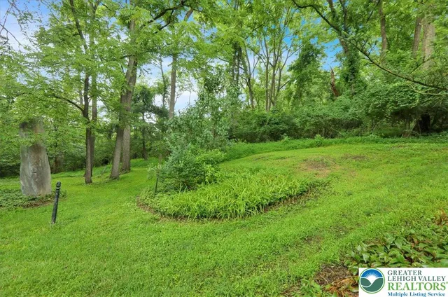 a view of backyard of house with wooden fence and trees