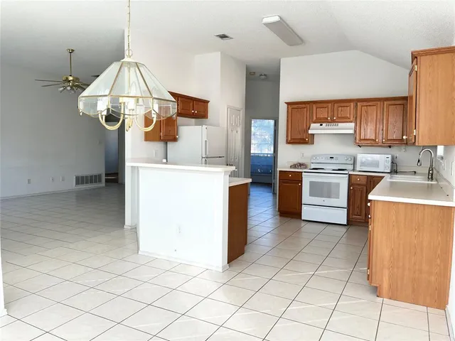 a kitchen with stainless steel appliances granite countertop a sink dishwasher a stove a refrigerator and a dining table with wooden floor