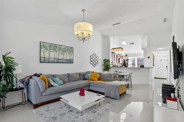 a living room with furniture kitchen view and a chandelier
