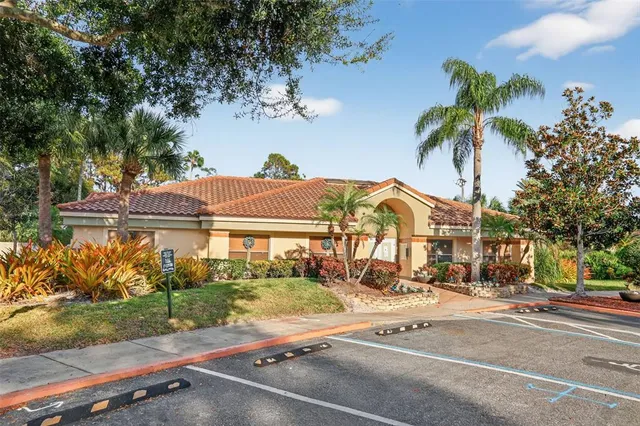 a view of a white house with a large tree and plants